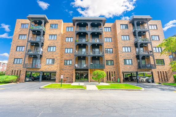 Front view of a multi-story brick apartment building with balconies.