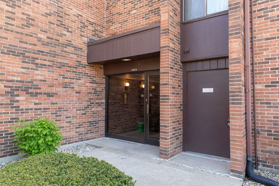 Entrance of a brick building with glass doors and a surrounding sidewalk.