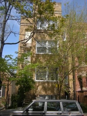 Front view of a multi-story brick building with trees in front.