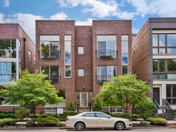 Front view of a multi-story brick building with large windows and balconies.