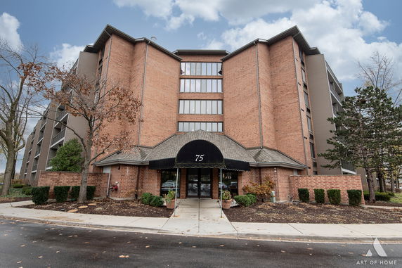 Front view of a multi-story brick building with large windows and a black entrance canopy.