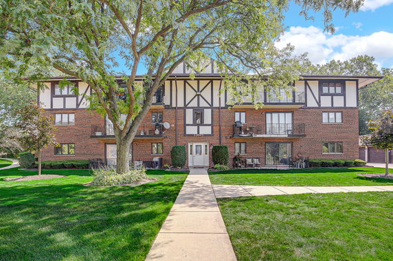 Front view of a three-story apartment building with a brick facade and balconies.
