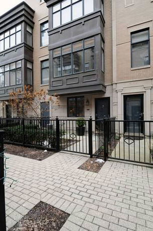 Front view of a multi-story building with large windows and a fenced entrance.