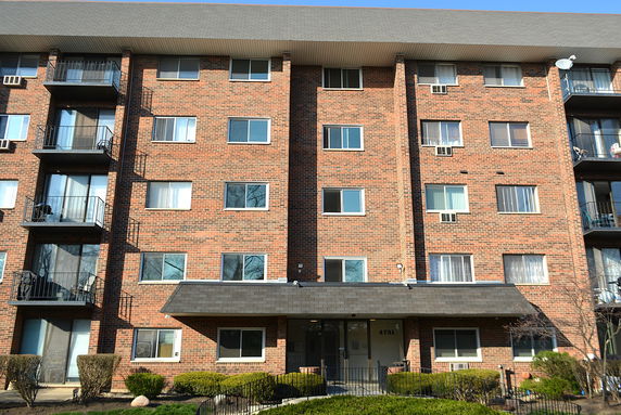 Front view of a multi-story brick apartment building with balconies.