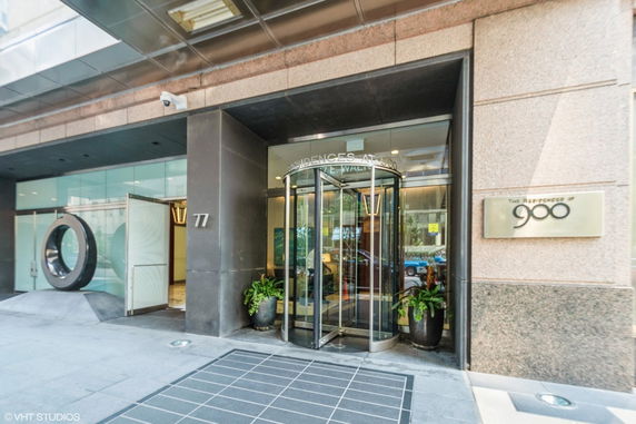 Front entrance of a building with a revolving door and metal facade.