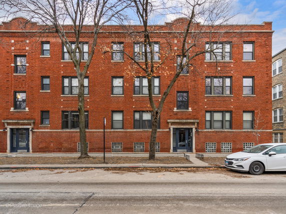 Front view of a multi-story red brick building with multiple windows and entrances.