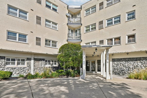 Front view of a multi-story building with a brick facade and entrance.