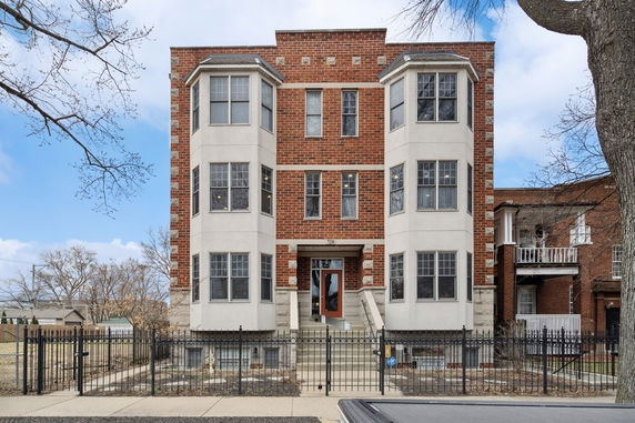 Front view of a multi-story brick building with bay windows and a central entrance.