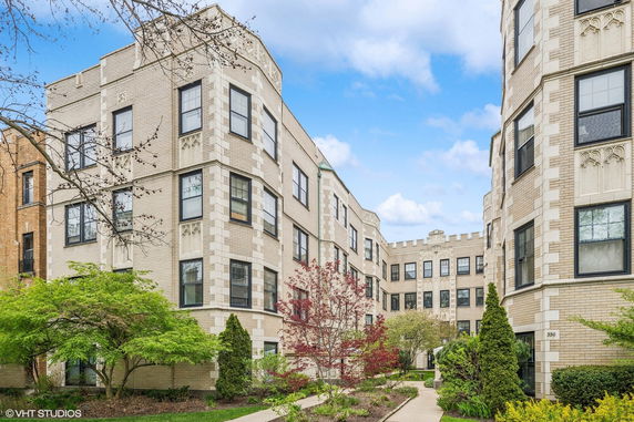 Front view of an apartment building with intricate brick design and landscaped garden.