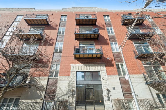 Front view of a multi-story brick apartment building with balconies.