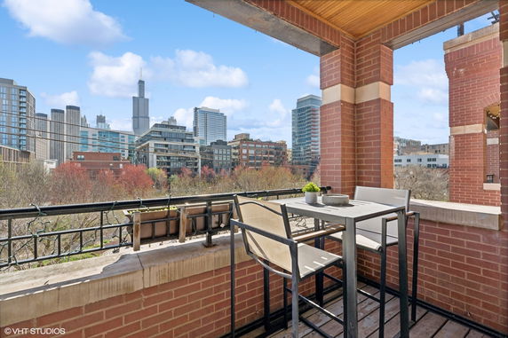View from a balcony with a table and chairs showing a city skyline.