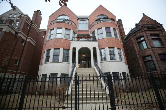 Front view of a three-story brick building with arched entrance and staircase.