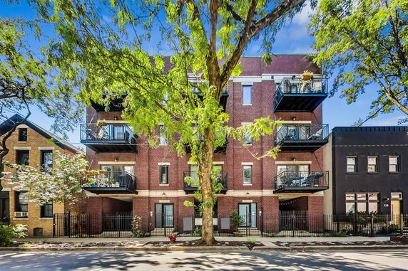 Front view of a multi-story brick apartment building with balconies.