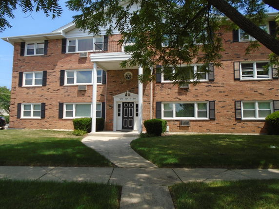 Front view of a three-story brick apartment building with multiple windows and a central entrance.