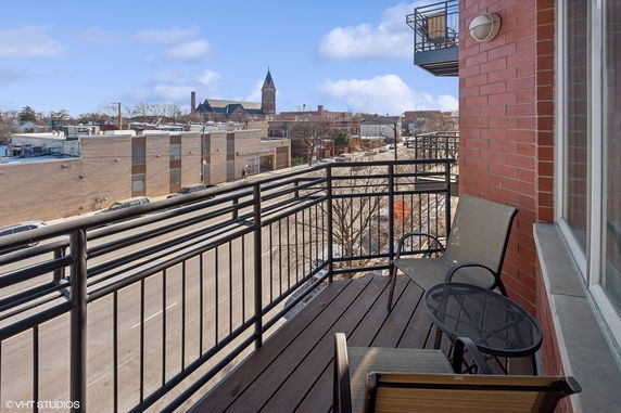 View from a balcony overlooking a street with buildings and a church in the background.