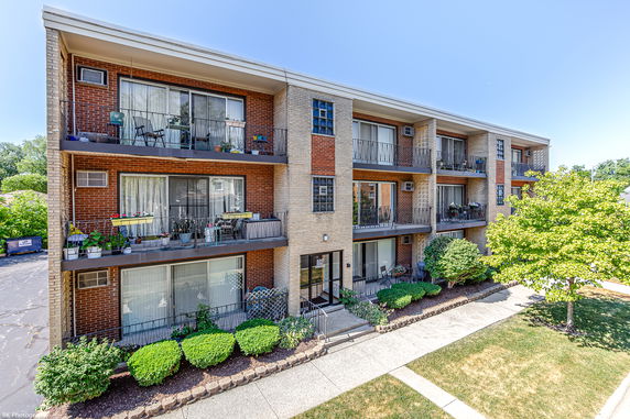 Front view of a three-story apartment building with balconies and brick facade.