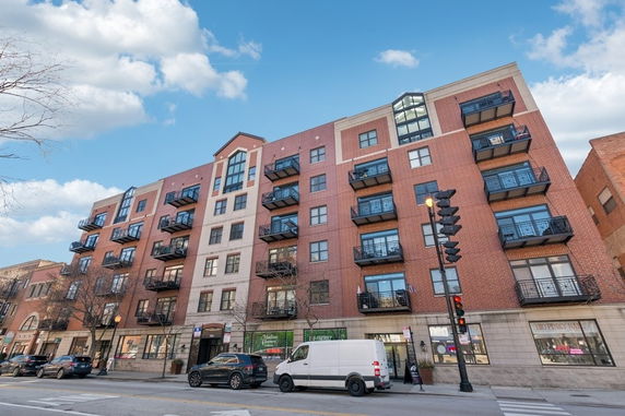 Front view of a multi-story apartment building with brick exterior and balconies.