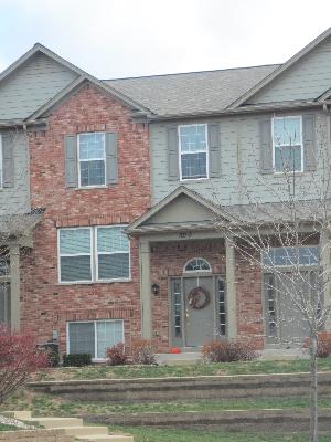 Front view of a brick townhouse with a gabled roof and front porch.