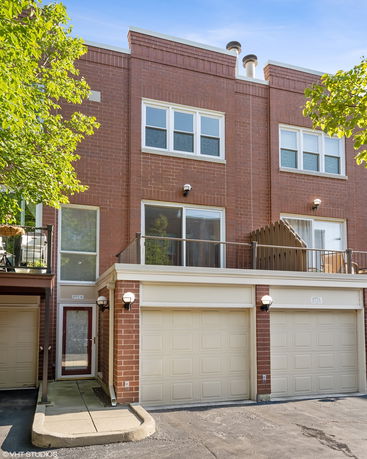 Front view of a multi-story brick townhouse with garages.