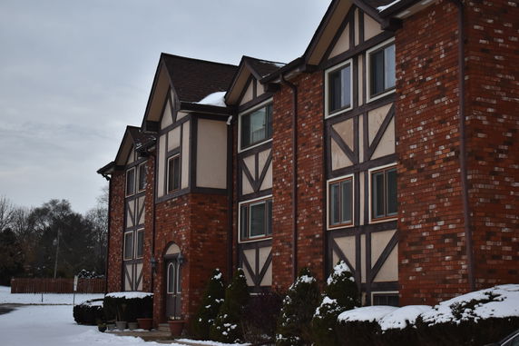 Front view of a multi-story brick building with gabled roofs and Tudor style architecture.