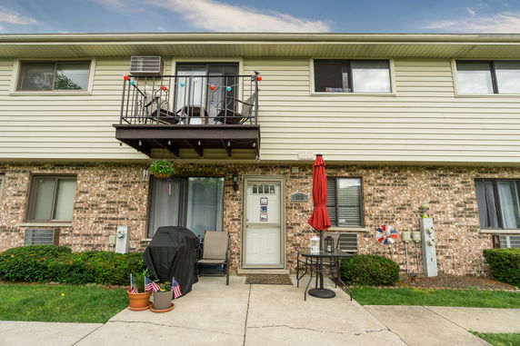 Front view of a two-story house with a small balcony and patio area.