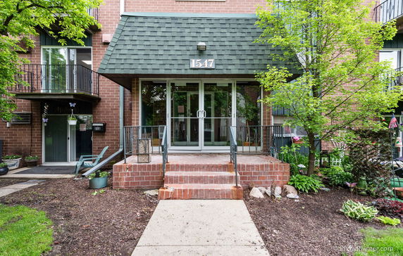 Front view of a multi-story brick building with a green awning and glass doors.