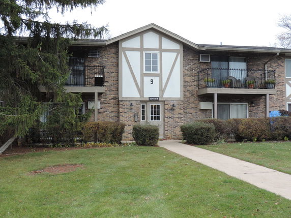 Front view of a two-story brick apartment building with balconies.