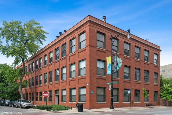 Front view of a three-story brick building on a city street corner.