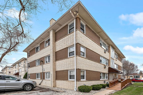 Front view of a three-story apartment building with brick exterior and multiple windows.