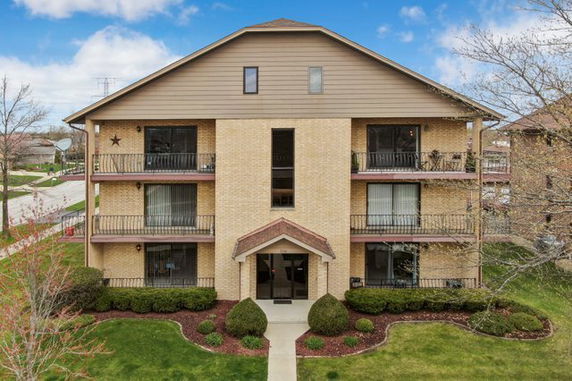 Front view of a three-story building with balconies and a gabled roof.