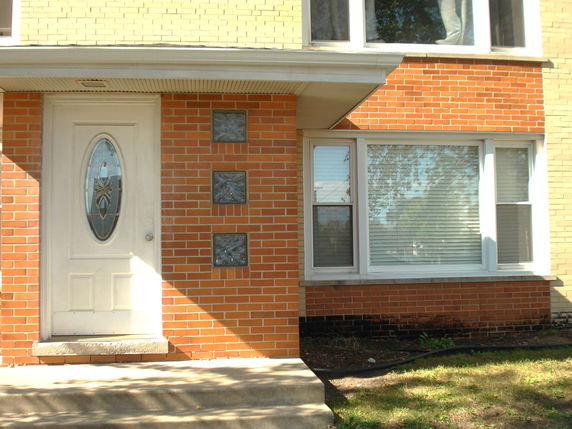 Front view of a brick house with a white door and large window.