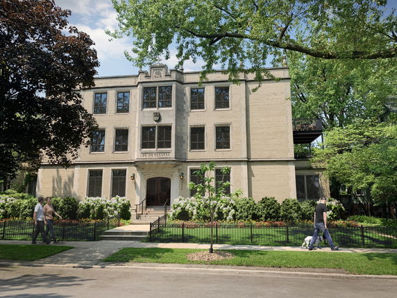 Front view of a multi-story residential building with a central entrance and multiple windows.