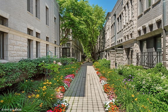 Pathway between two residential buildings with landscaped gardens.