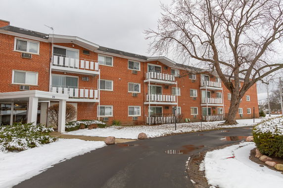 Front view of a multi-story brick apartment building with balconies.