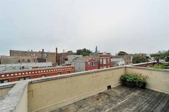 Rooftop with wooden decking and a view of urban buildings.