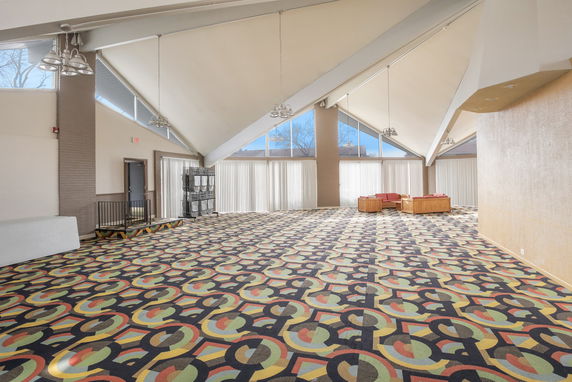Spacious indoor area with patterned carpet and high ceilings.