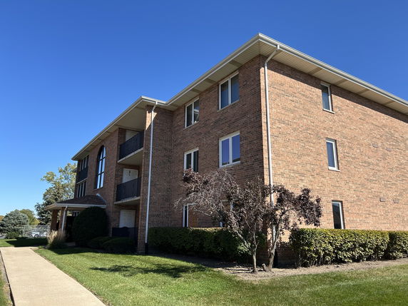 Front view of a three-story brick building with balconies.