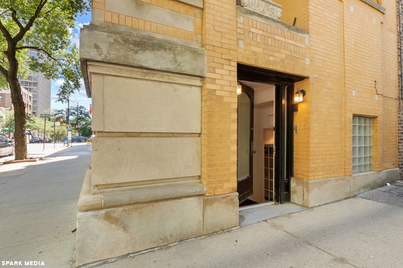 Brick building with an open entrance door facing the street.