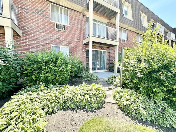 Front view of a multi-story brick apartment building with balconies and sliding doors.