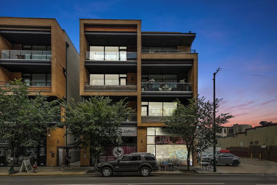 Front view of a modern multi-story building with balconies and large windows.