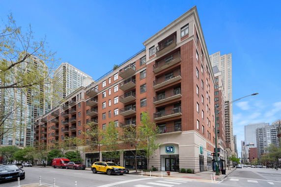 Front view of a multistory brick apartment building on a city street corner.