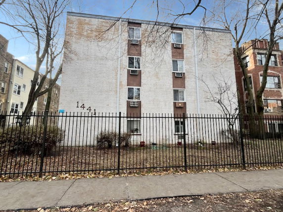 Front view of a multi-story building with a gated entrance.