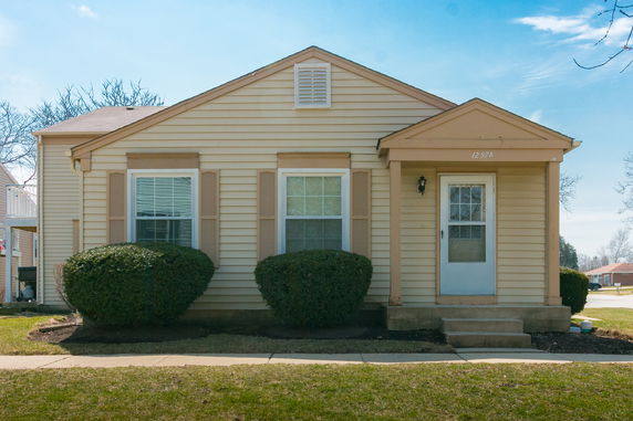 Front view of a single-story house with two windows and a porch.
