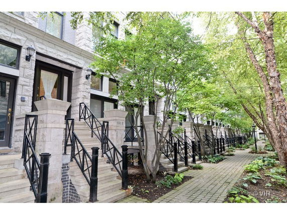 Front view of a row of townhouses with stone exterior and staircases leading to the entrances.
