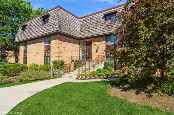 Front view of a two-story brick building with a shingled roof and landscaped entrance.