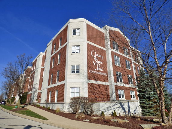 Front view of a multi-story condominium building with brick and light-colored accents.