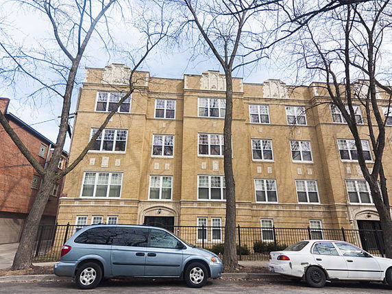 Front view of a multi-story residential building with multiple windows and decorative brickwork.