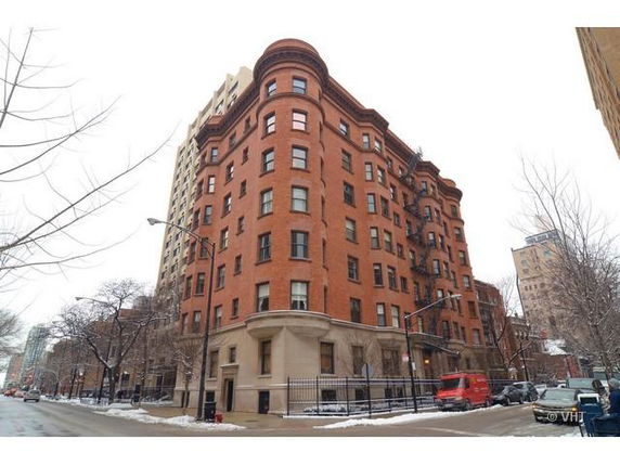 Front view of a multi-story brick apartment building on a street corner.