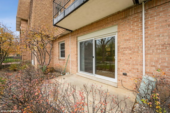 View of a brick building with a balcony and sliding glass door.