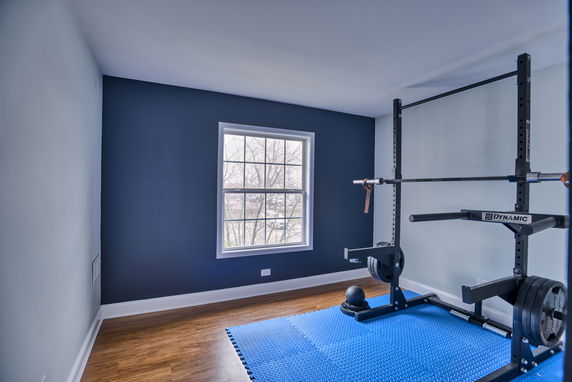 Home gym room with exercise equipment and a window.